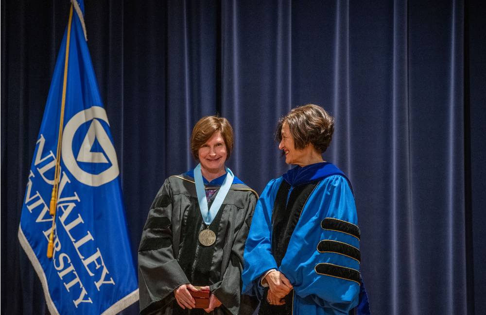 Provost Mili smiles at faculty member on stage